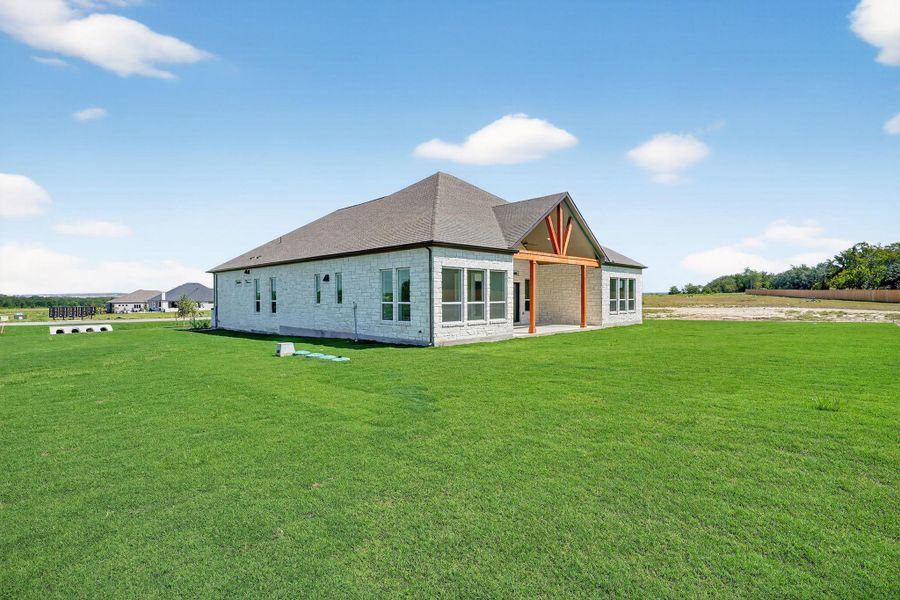Back of house with a patio, a yard, roof with shingles, and brick siding Back of house with a patio, a yard, roof with shingles, and brick siding
