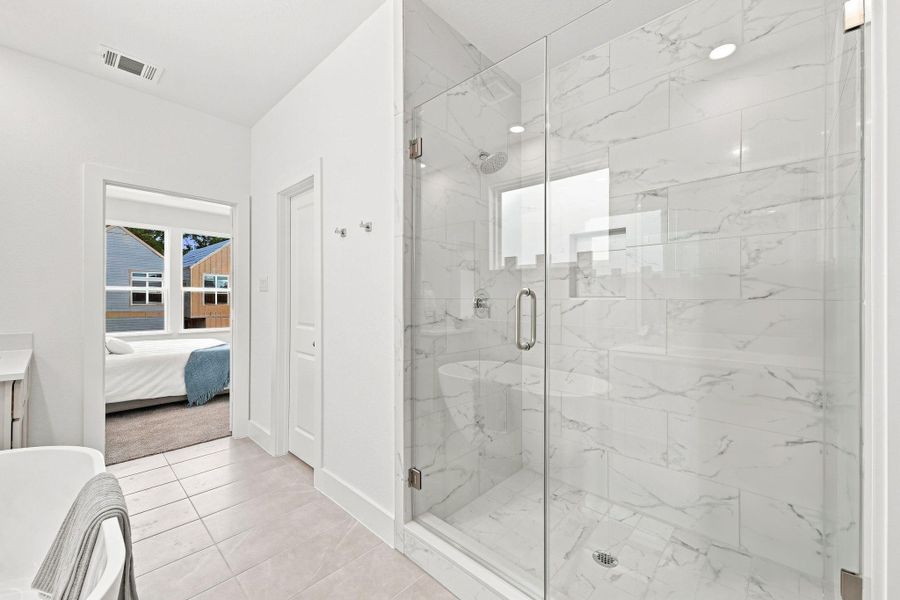 Spacious separate shower featuring a frameless glass enclosure, elegant floor-to-ceiling tile, built-in niche and modern fixtures. Spacious separate shower featuring a frameless glass enclosure, elegant floor-to-ceiling tile, built-in niche and modern fixtures.