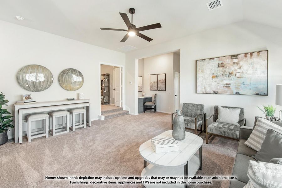Carpeted living room with ceiling fan, gray seating, console table, and open doorway to home office Carpeted living room with ceiling fan, gray seating, console table, and open doorway to home office