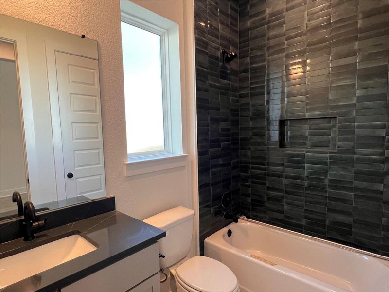 Bathroom featuring a textured wall, vanity, and shower / washtub combination