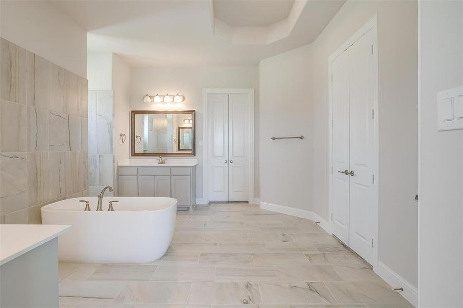 Bathroom with a washtub, tile patterned floors, and vanity