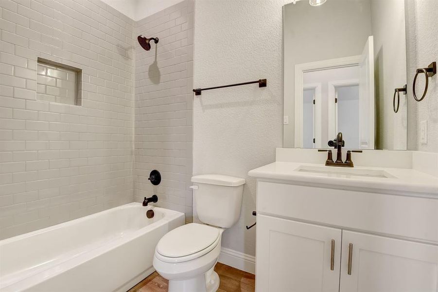 Full bathroom with wood-type flooring, tiled shower / bath, toilet, and large vanity