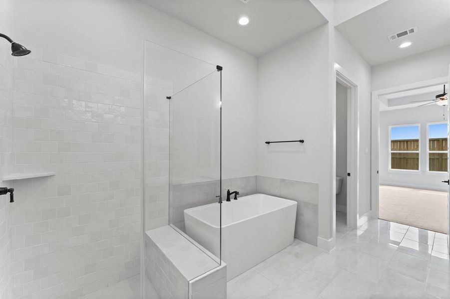 Separate Shower with Seat and Shampoo Shelf, Freestanding Tub, and Enclosed Toilet.