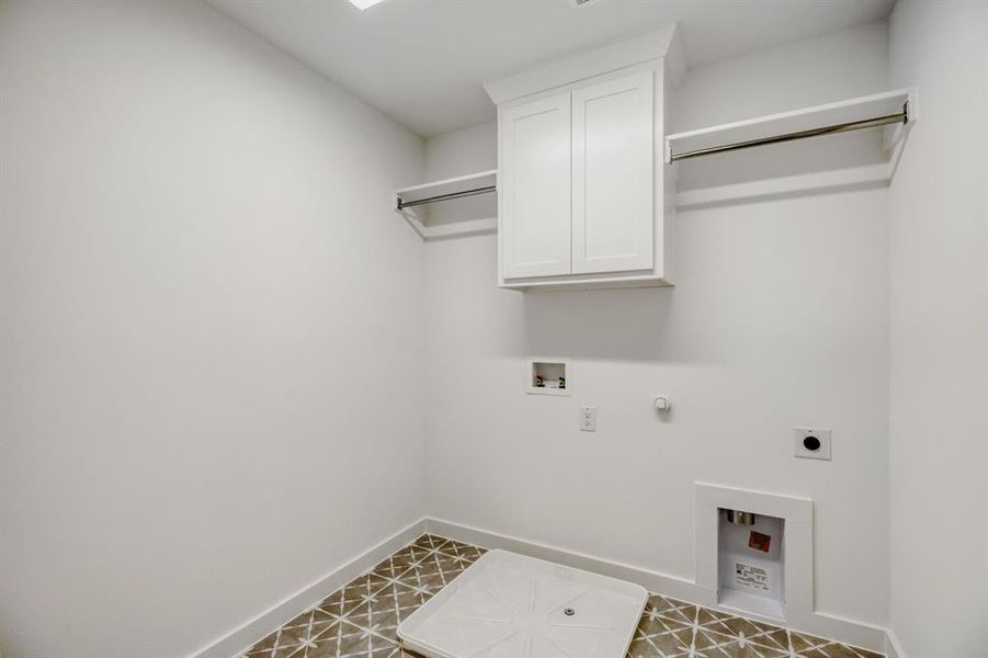 Utility room featuring patterned floor tile, white wall cabinetry, and dual clothing rods