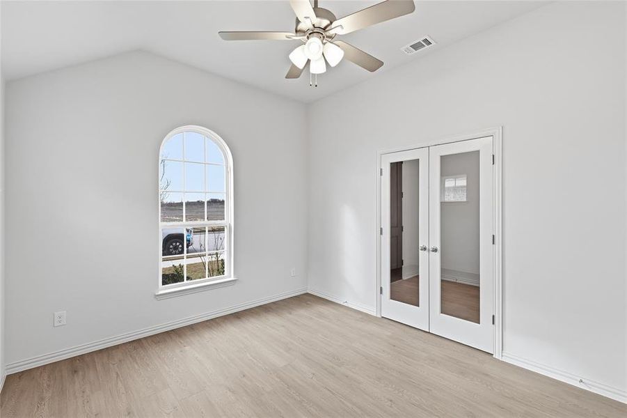 Unfurnished bedroom with french doors, a ceiling fan, light wood-style flooring, a closet, and lofted ceiling