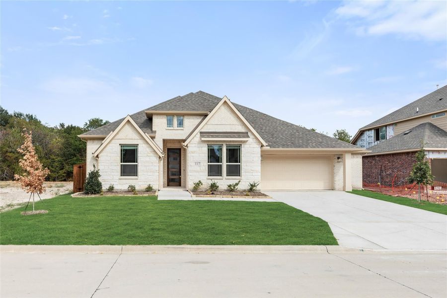 Single-story home with cream stone exterior, two-car garage, and manicured front lawn