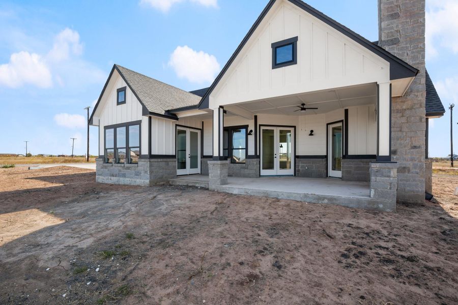 A newly constructed modern farmhouse boasts a covered patio, perfect for outdoor living, with a striking stone chimney and board-and-batten siding. A newly constructed modern farmhouse boasts a covered patio, perfect for outdoor living, with a striking stone chimney and board-and-batten siding.