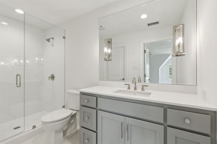 Bathroom featuring tile patterned flooring, walk in shower, vanity, and toilet