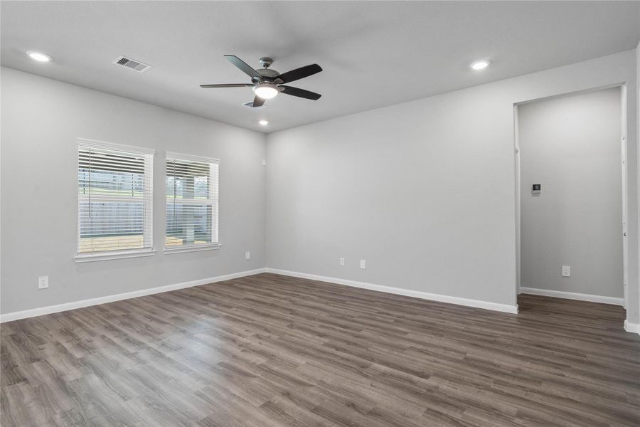 A bright and airy open-concept space featuring luxury vinyl flooring, high ceilings with recessed lighting and ceiling fan, and abundant natural light from large windows (fitted with blinds). A bright and airy open-concept space featuring luxury vinyl flooring, high ceilings with recessed lighting and ceiling fan, and abundant natural light from large windows (fitted with blinds).