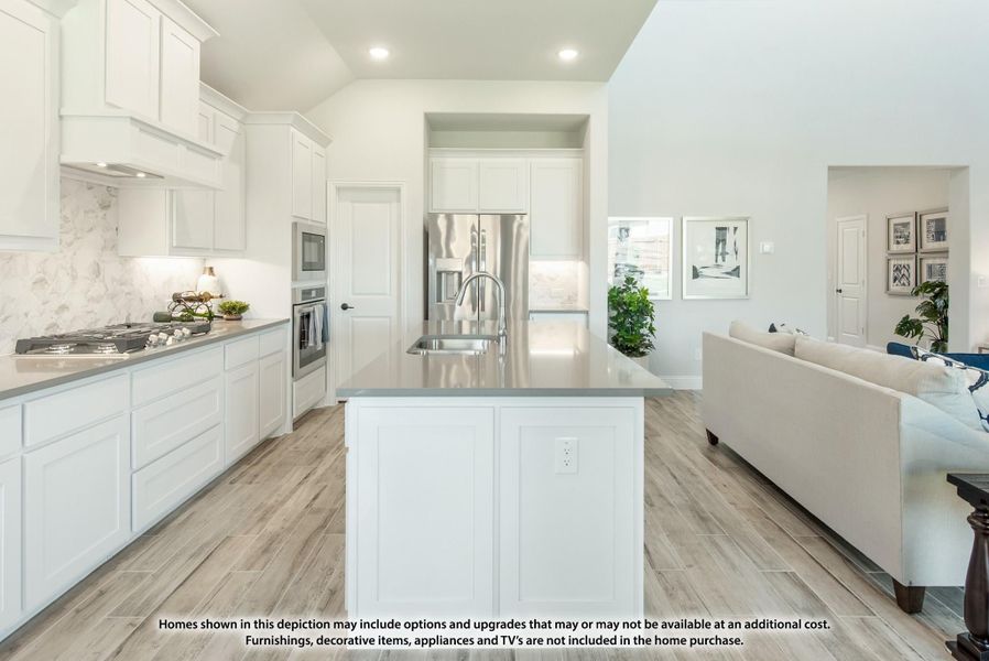 Open kitchen with white cabinets, center island, stainless steel appliances, and light wood-look tile floors opening to living area.