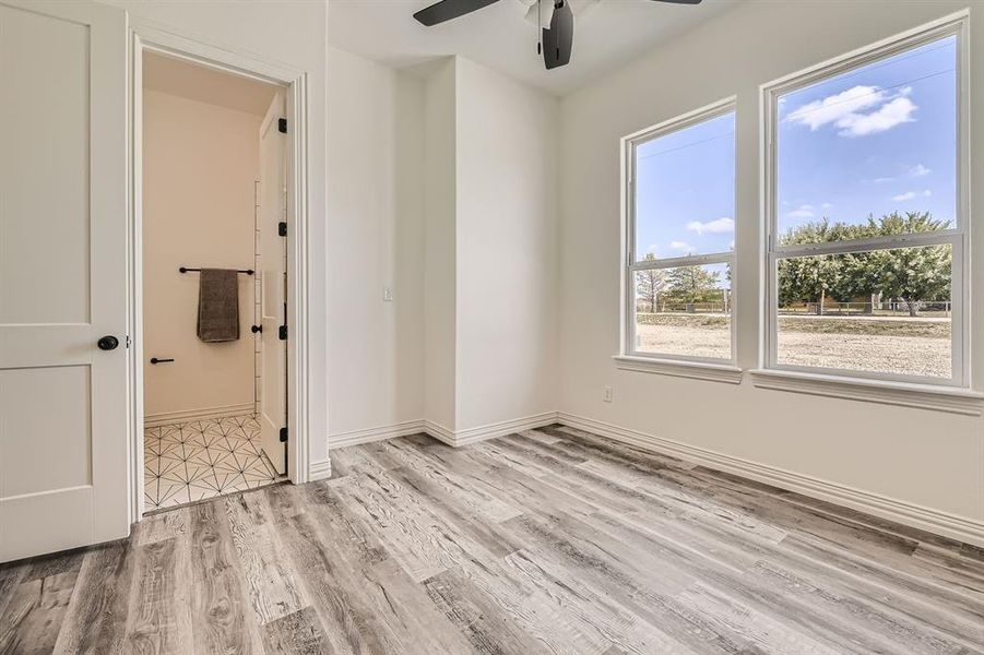 Unfurnished bedroom featuring light hardwood / wood-style floors, ceiling fan, and ensuite bathroom