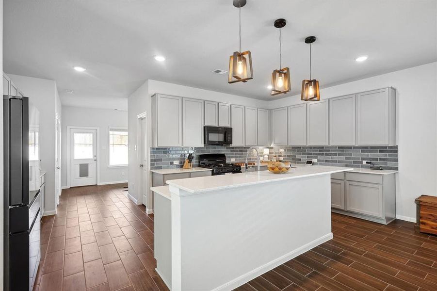 Kitchen featuring a center island with sink, black appliances, and dark hardwood / wood-style floors