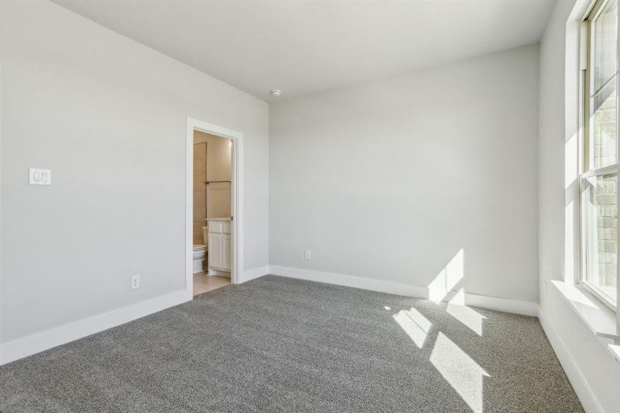 Unfurnished bedroom with multiple windows, carpet, and ensuite bath