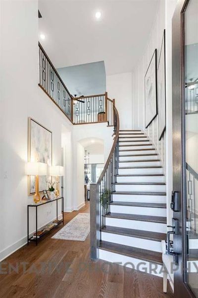 Stairway with wood finished floors, a towering ceiling, and recessed lighting Stairway with wood finished floors, a towering ceiling, and recessed lighting