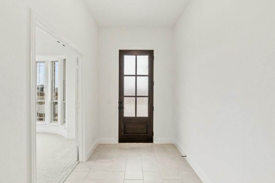 Entryway with dark wood glass-panel front door, white walls, and light tile floors