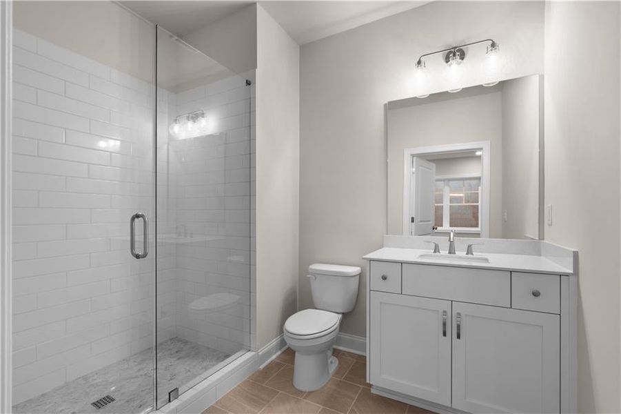 Full bath with vanity, a stall shower, and light tile patterned flooring