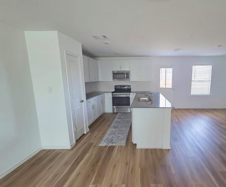 Kitchen with stainless steel appliances, white cabinets, light wood finished floors, open floor plan, and a peninsula Kitchen with stainless steel appliances, white cabinets, light wood finished floors, open floor plan, and a peninsula