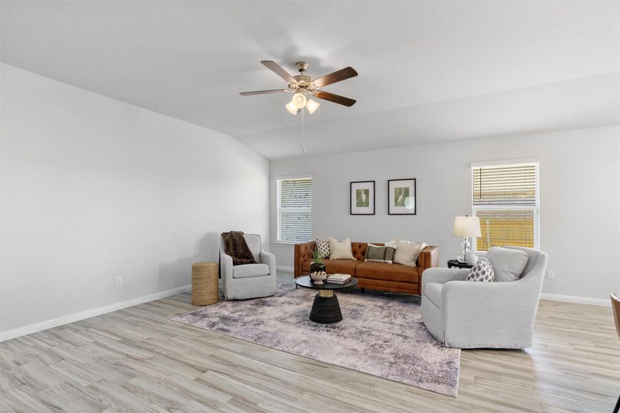 Living room featuring light wood-style flooring, vaulted ceiling, and a ceiling fan