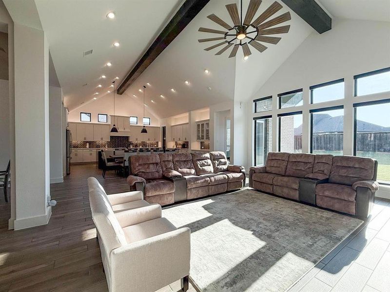 Living room with beamed ceiling, high vaulted ceiling, a ceiling fan, recessed lighting, and dark wood finished floors Living room with beamed ceiling, high vaulted ceiling, a ceiling fan, recessed lighting, and dark wood finished floors