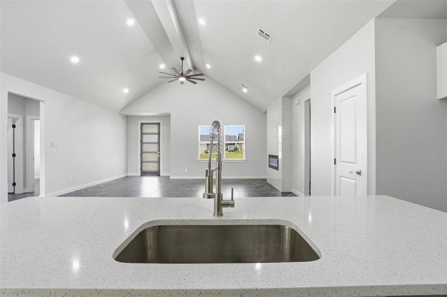 Kitchen island featuring a stainless steel sink with a modern faucet set into a light-colored speckled countertop