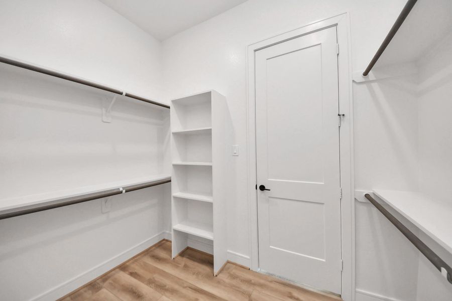 Generous walk-in closet featuring built-in shelving, high ceilings, and ample space for organized storage and wardrobe display.