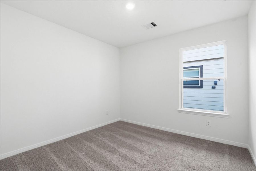 Secondary bedroom features plush carpet flooring, neutral paint, recessed lighting, large window, and a walk-in closet.