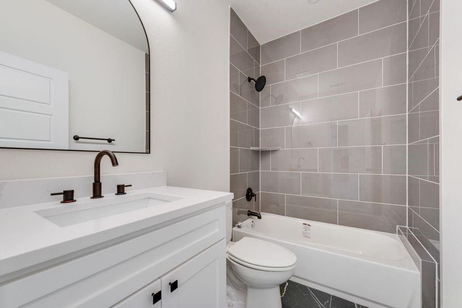 Full bathroom with toilet, tiled shower / bath combo, and vanity