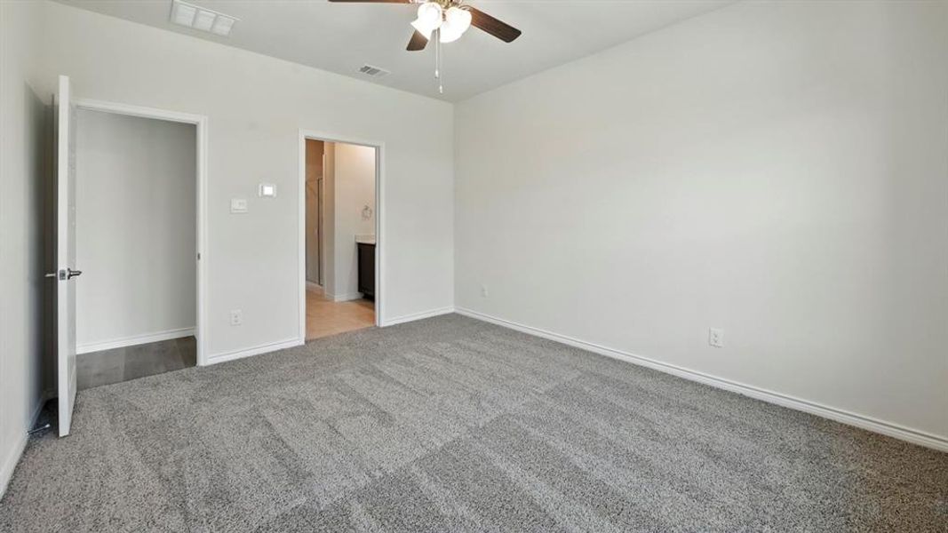 Unfurnished bedroom featuring carpet, ceiling fan, and ensuite bath