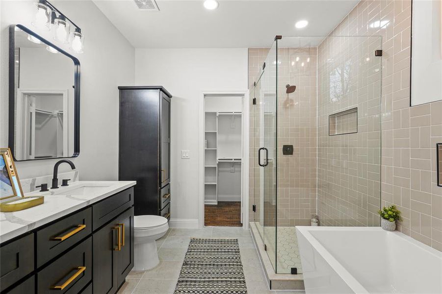 Full bathroom featuring double vanity, a freestanding bath, a shower stall, a walk in closet, and recessed lighting