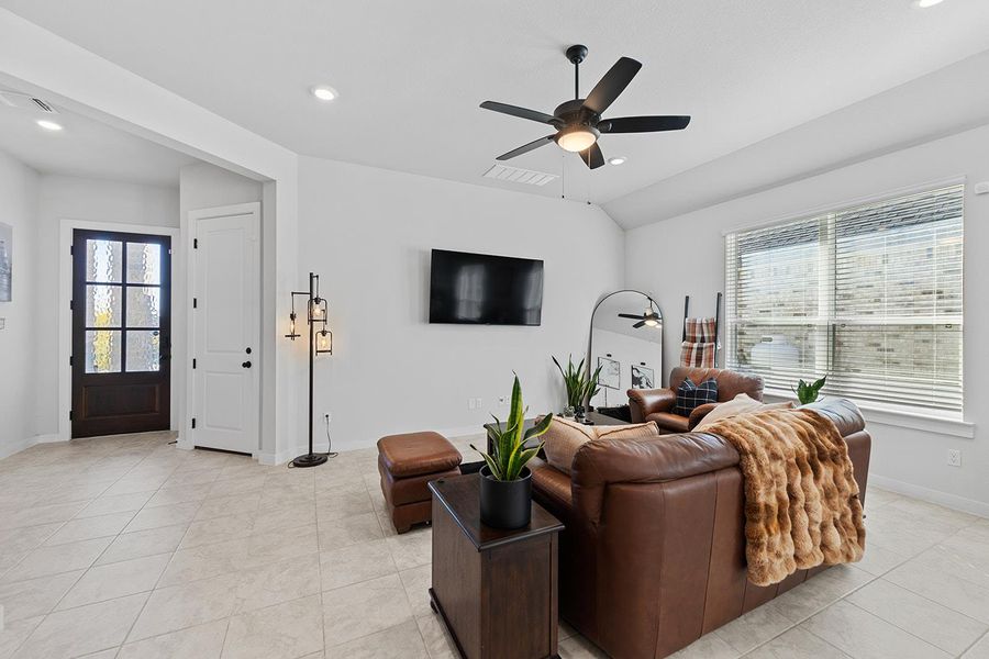 Living room with a ceiling fan, recessed lighting, vaulted ceiling, and light tile patterned flooring