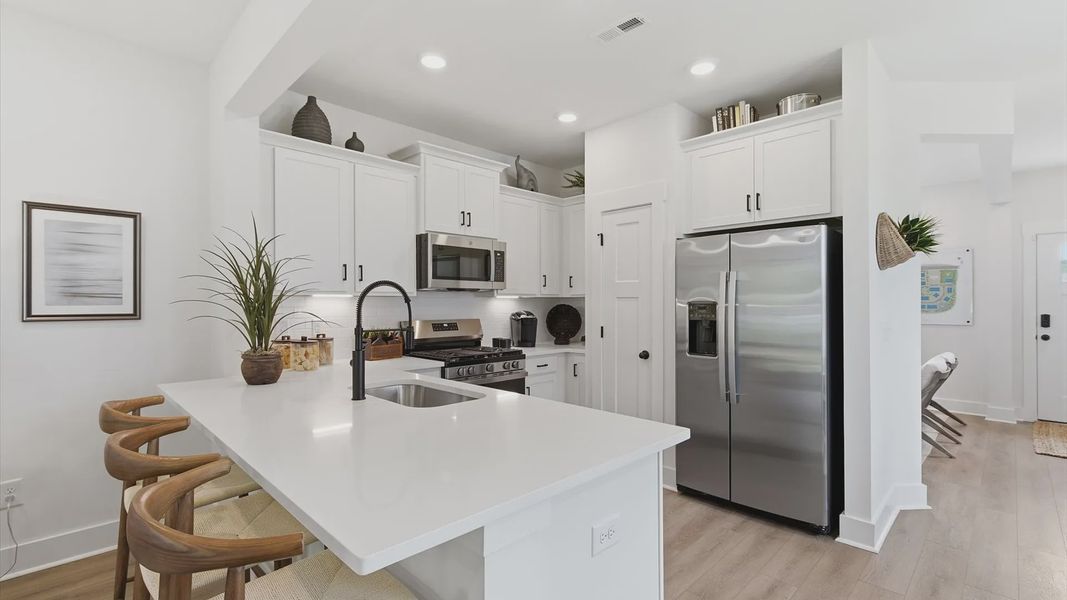 Superior kitchen with quartz countertops, modern lighting, and room for entertaining at Clarke Townes