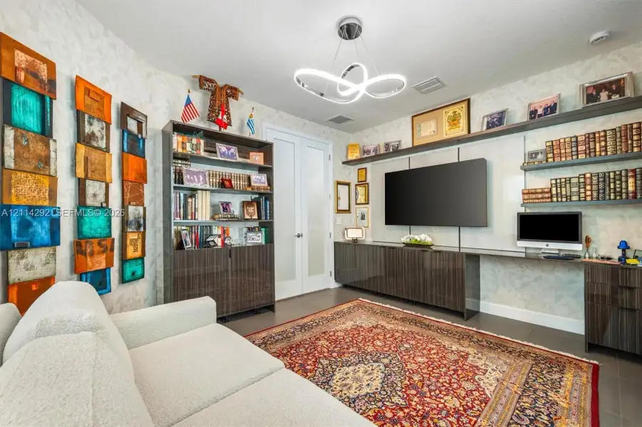 Custom built-in cabinetry with integrated workspace, floating wall shelving, modern minimalist ceiling fixture, and double glass-panel doors