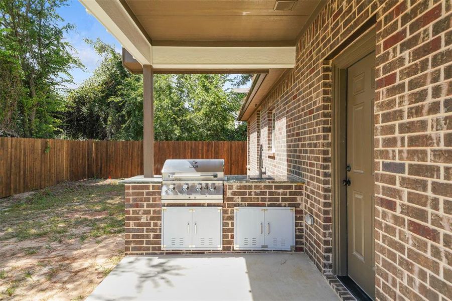 Covered patio featuring an outdoor kitchen with built-in grill and integrated storage cabinets