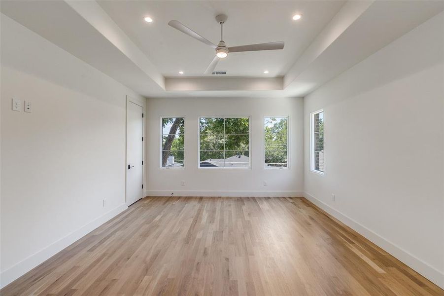 Unfurnished room featuring a raised ceiling, light wood-style floors, ceiling fan, and recessed lighting Unfurnished room featuring a raised ceiling, light wood-style floors, ceiling fan, and recessed lighting