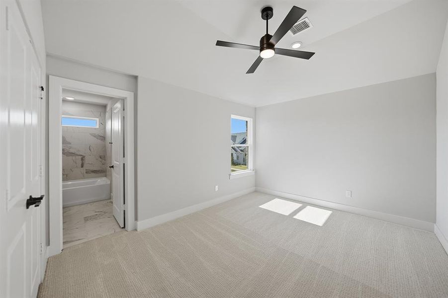 Unfurnished bedroom with a ceiling fan, ensuite bathroom, and light carpet