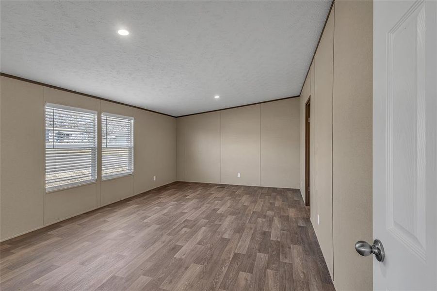 Empty room featuring a textured ceiling, crown molding, and hardwood / wood-style flooring