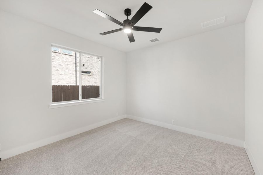 Empty bedroom with white walls, carpet flooring, black ceiling fan, and a single window