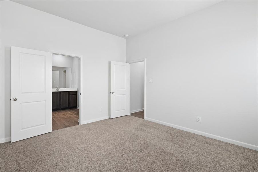 Unfurnished bedroom with ensuite bath and carpet Unfurnished bedroom with ensuite bath and carpet