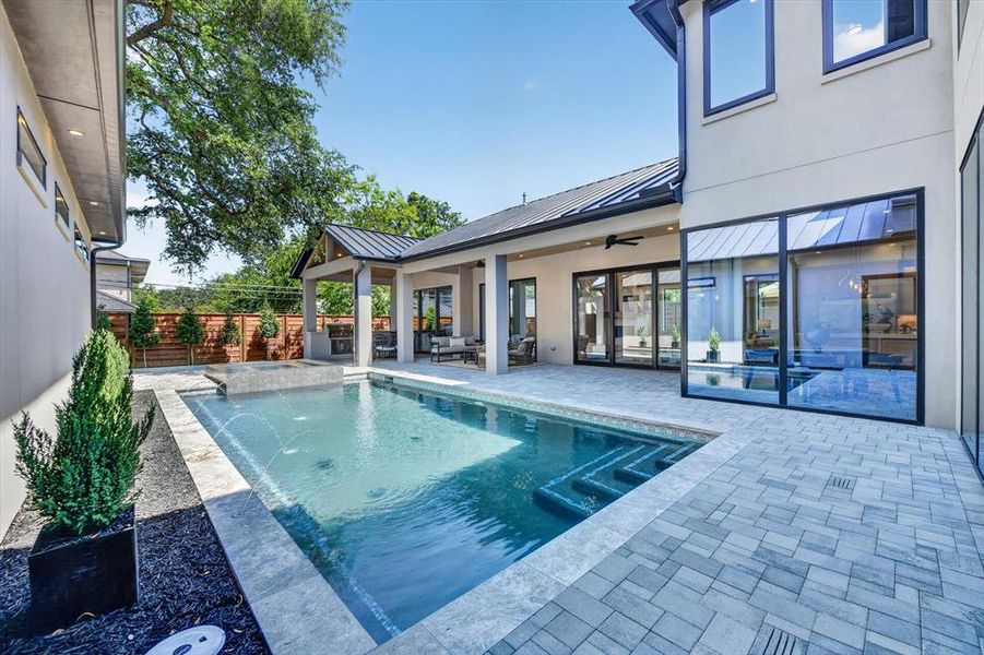 Private backyard oasis featuring a rectangular swimming pool with integrated spa and water features Private backyard oasis featuring a rectangular swimming pool with integrated spa and water features