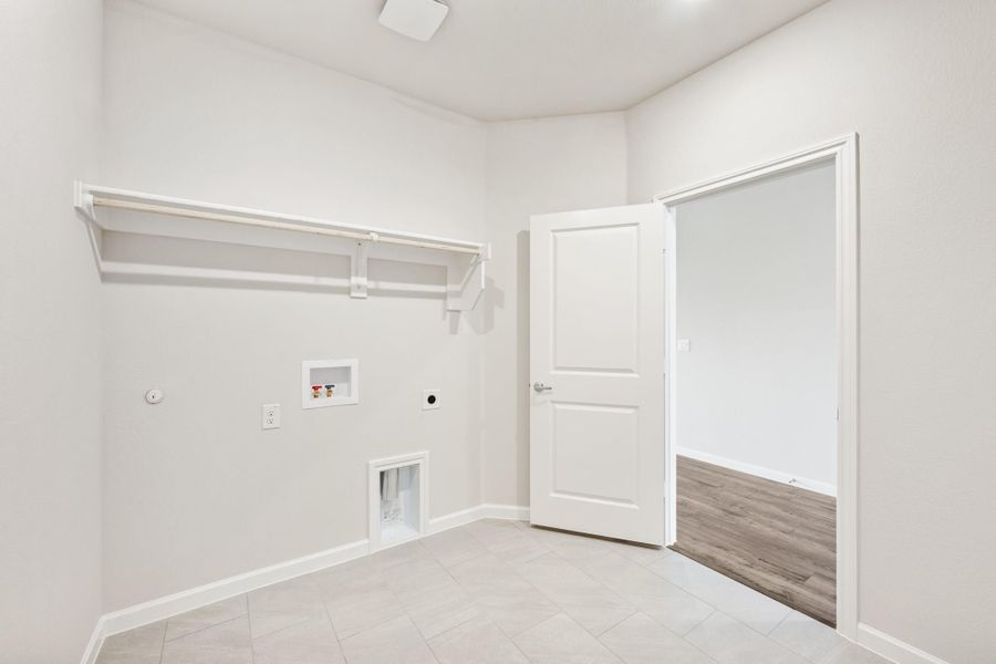 Laundry room with wall-mounted shelf, washer hookups, pet door, and tile flooring