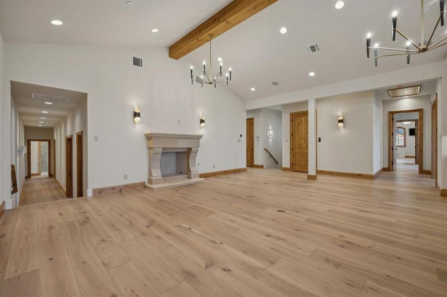Unfurnished living room with a chandelier, recessed lighting, light wood-style floors, beam ceiling, and high vaulted ceiling