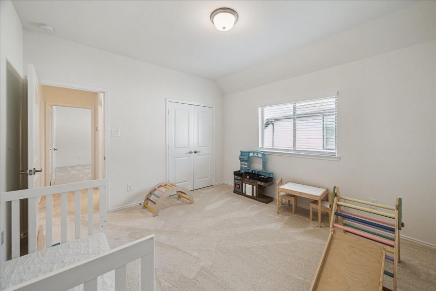 Bright and airy upstairs secondary bedroom with ample space, a French door closet, and generous natural light.