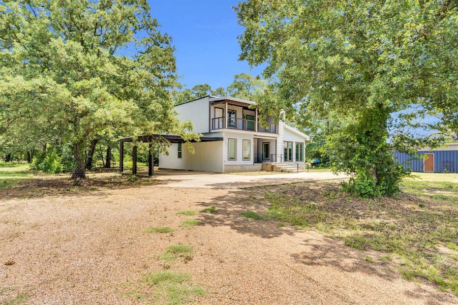 Mid-century modern home featuring a balcony and dirt driveway