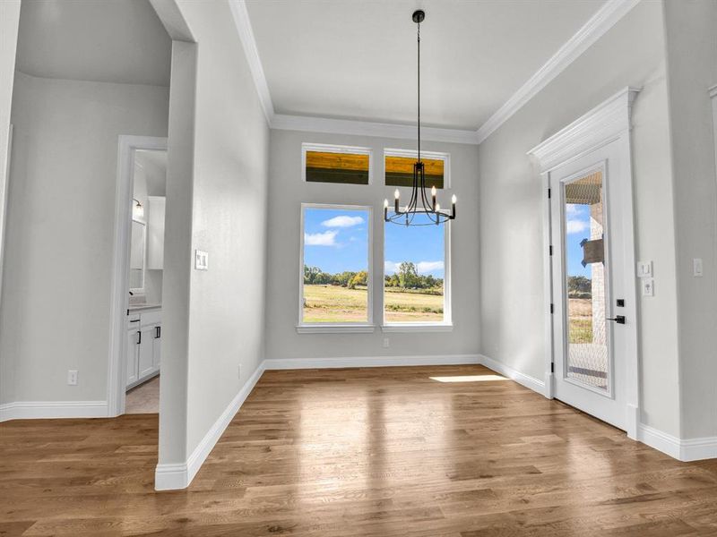 Unfurnished dining area featuring crown molding, wood-type flooring, and an inviting chandelier