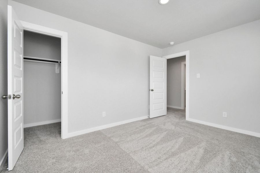 Secondary bedroom. Plush carpet, neutral paint color, large windows, and spacious closets. Sample photo of completed home with similar floor plan. Actual colors and selections may vary.