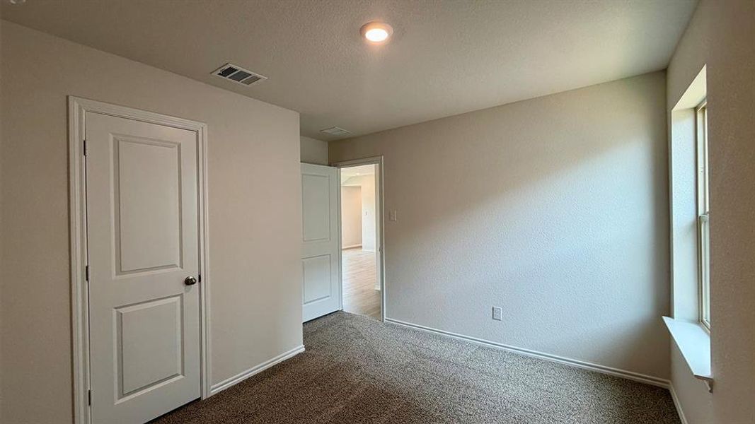 Carpeted room featuring a single window with a deep sill, a recessed ceiling light, and a white paneled door