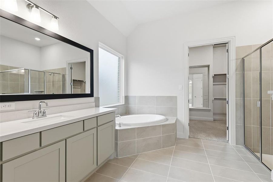 Full bath featuring a walk in closet, a shower stall, a bath, vanity, and light tile patterned floors