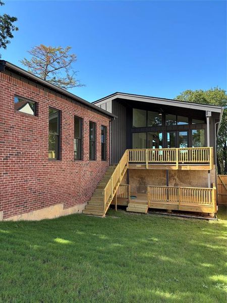 Rear view of property with a wooden deck, stairway, a lawn, and board and batten siding