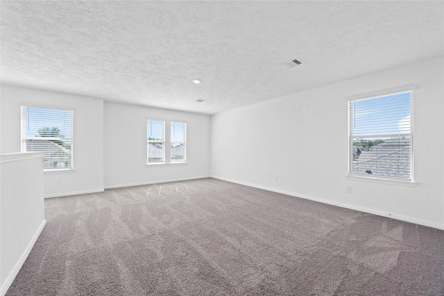 Head upstairs and enjoy the Loft—an additional living area perfect for a game room, media space, or a peaceful retreat. Featuring plush carpet flooring, neutral paint, high ceilings, recessed lighting, and windows with blinds.