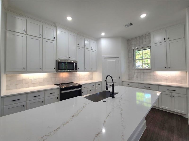 Kitchen featuring range with electric cooktop, sink, and white cabinets